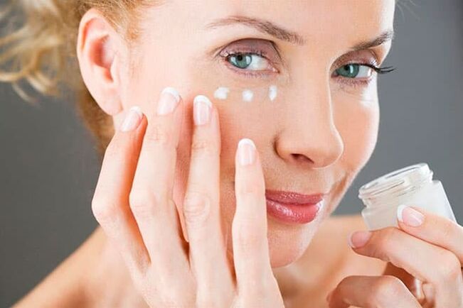 La mujer aplica crema facial con efecto antienvejecimiento. 